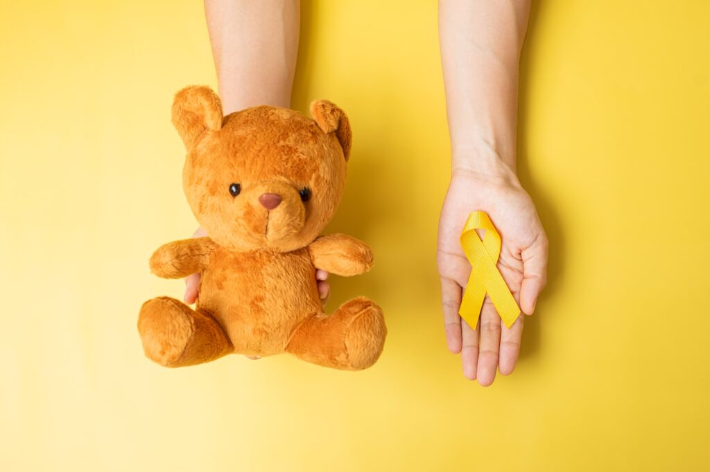 hand holding Yellow Ribbon and Bear doll for September Childhood Cancer